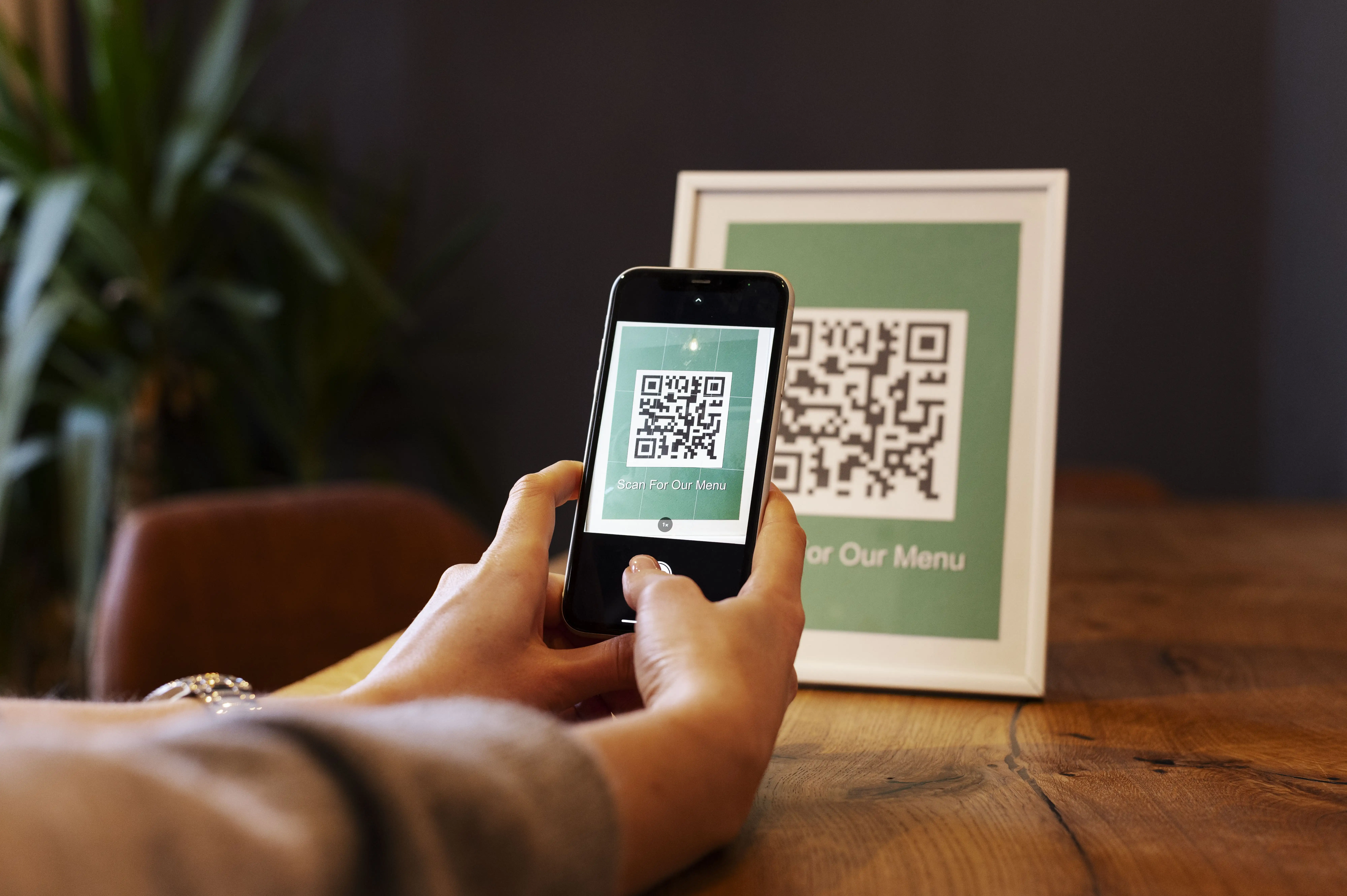 Hand scanning framed "Our Menu" QR code with smartphone for restaurant digital menu access
