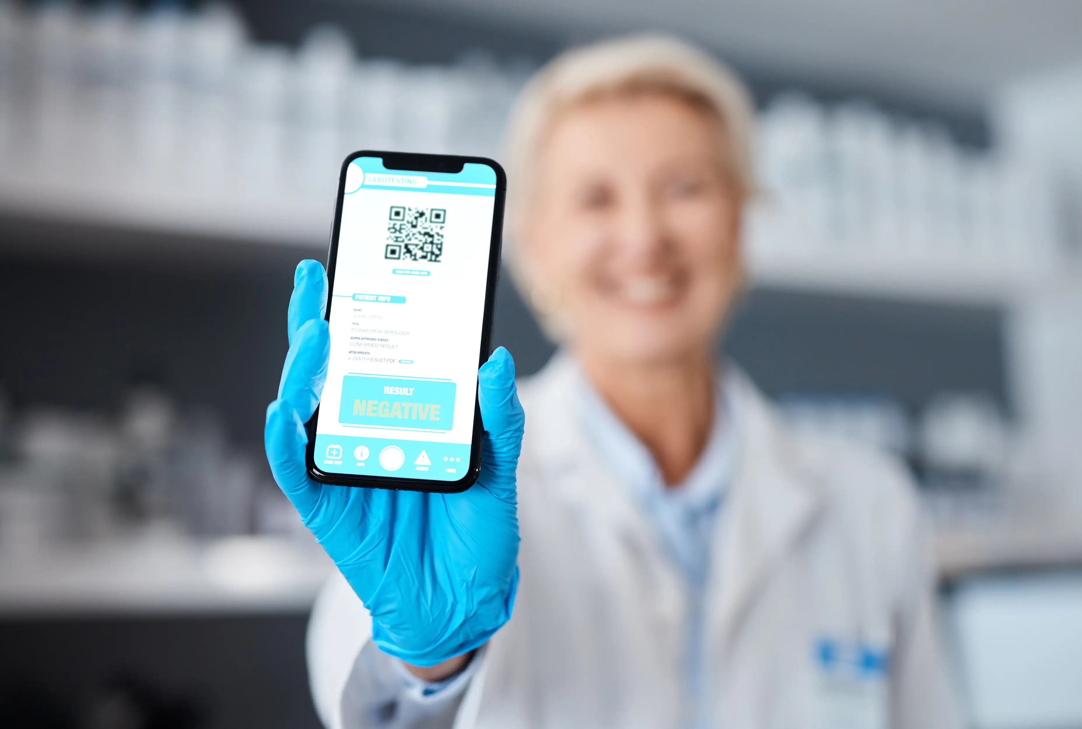 Healthcare professional in blue gloves displaying smartphone with QR code and negative medical test result screen in clinical laboratory setting for digital health records
